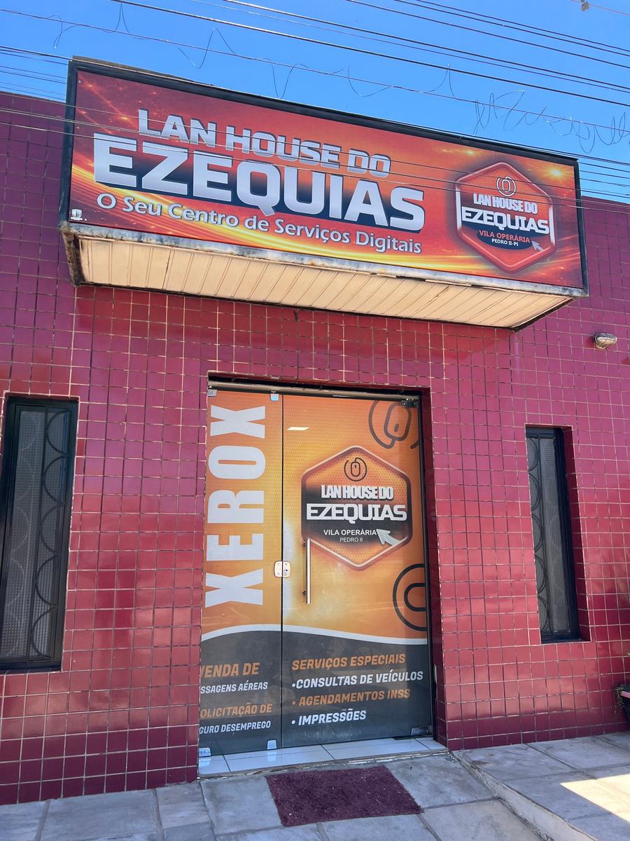 Fachada da Lan House do Ezequias, com placa laranja e porta de vidro adesivada
